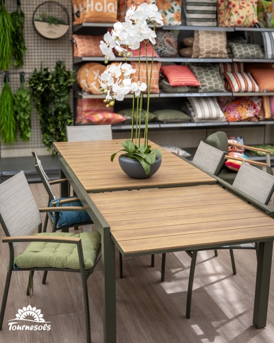 Ensemble de table de jardin extensible avec plateau effet bois et chaises en métal vert dans un magasin.